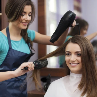 Friseurin föhnt einer Kundin die Haare